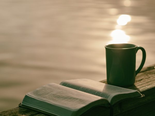 bible open with coffee mug with water in background